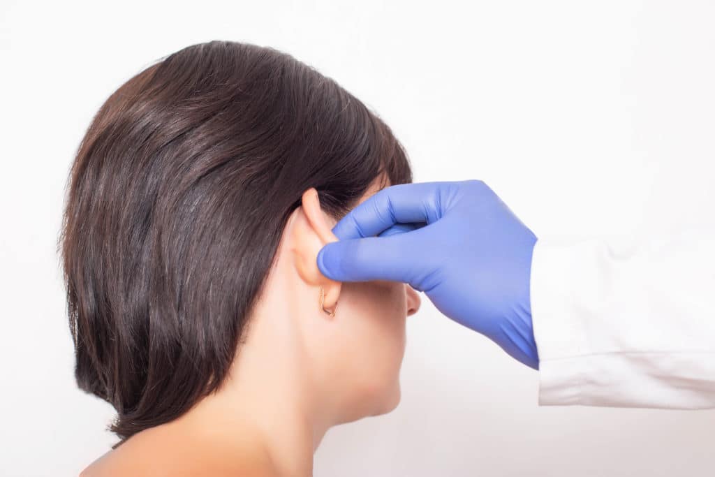 A woman getting her earlobe examined by a doctor.