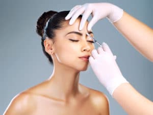 Studio shot of an attractive young woman receiving a botox injection in her face